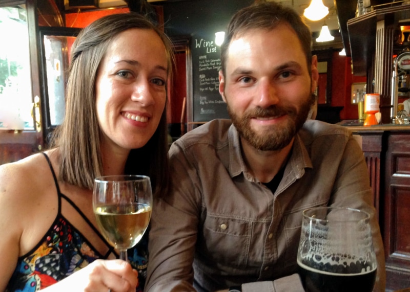 Two people, looking forward, holding drinks at a pub.