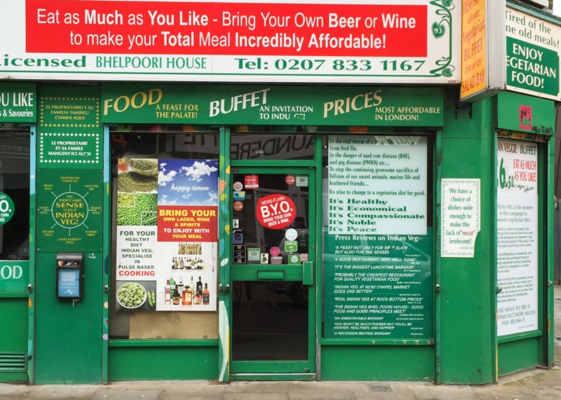 Green restaurant facade with windows and door, covered in signage.