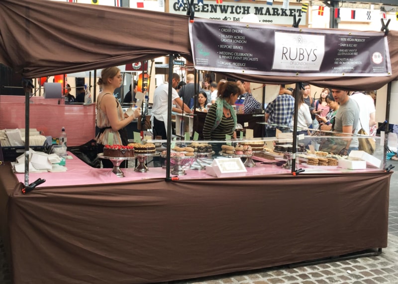 Brown and pink market stall with servers and onlookers.
