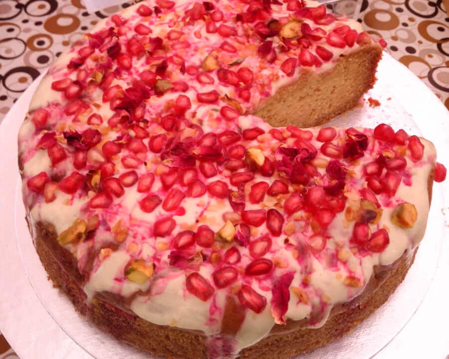 Pistachio cake topped with pomegranate and rose petals.