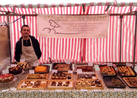 Red-striped market stall with rows of baked goods, server inside.