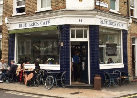 Blue-tiled restaurant facade with large windows and open door. Customers sitting outside.