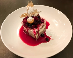 Piece of ice cream and cookie cake topped with red berries.