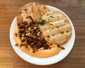 Hummus with pine nuts and two pieces of flat bread.