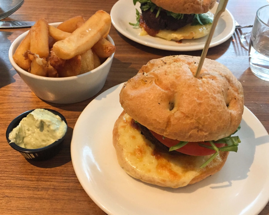 Two burgers with chips and side of mayo.