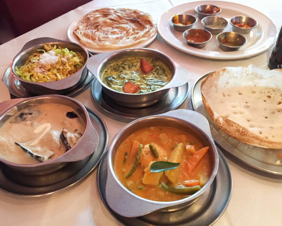 Assorted dishes of curries, sides, rice and paratha bread.