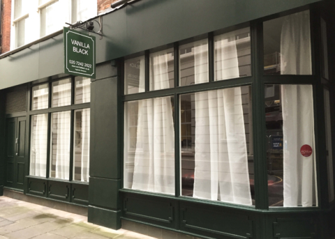 Green restaurant facade with white curtained windows.