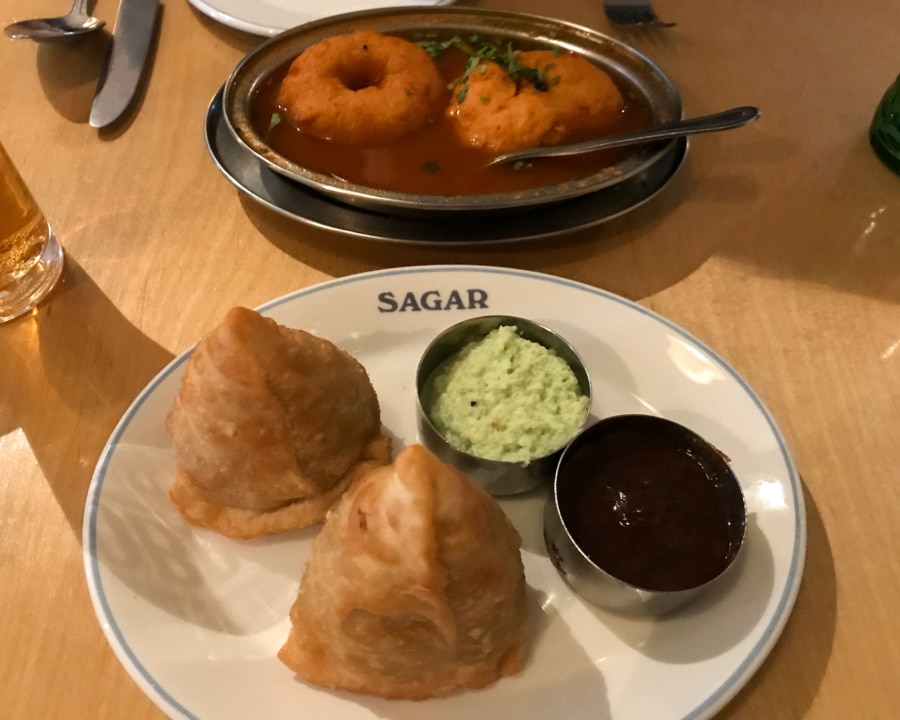 Two samosas with dips. Two lentil donuts in soup.